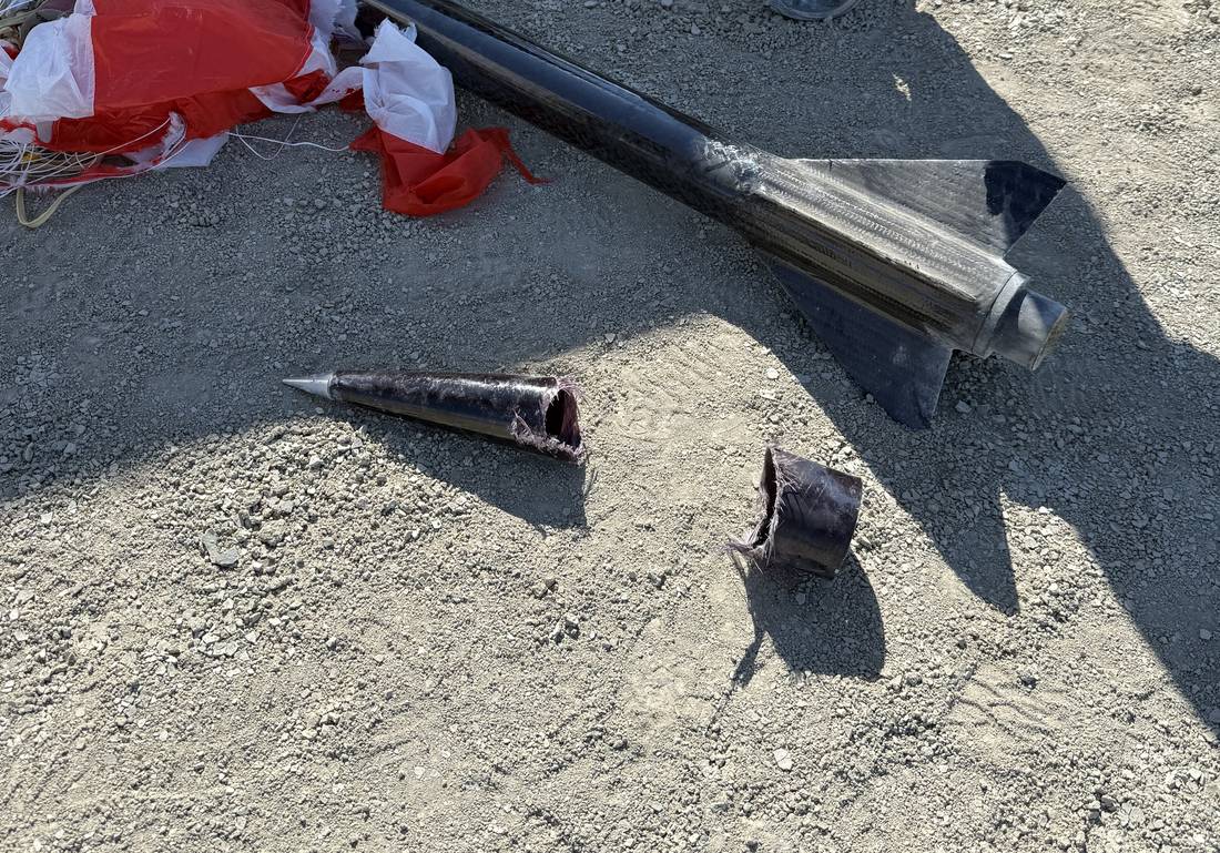 ION 4.3 back on the playa: the carbon airframe and fin can intact, the parachute beside it, and the nose cone in two torn sections